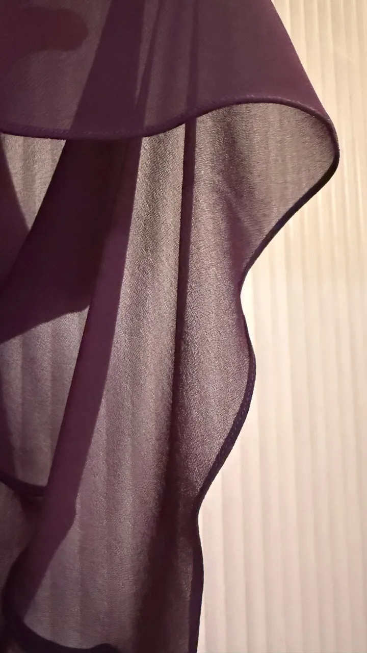 The softly draped purple hem of a double-layer chiffon dress.