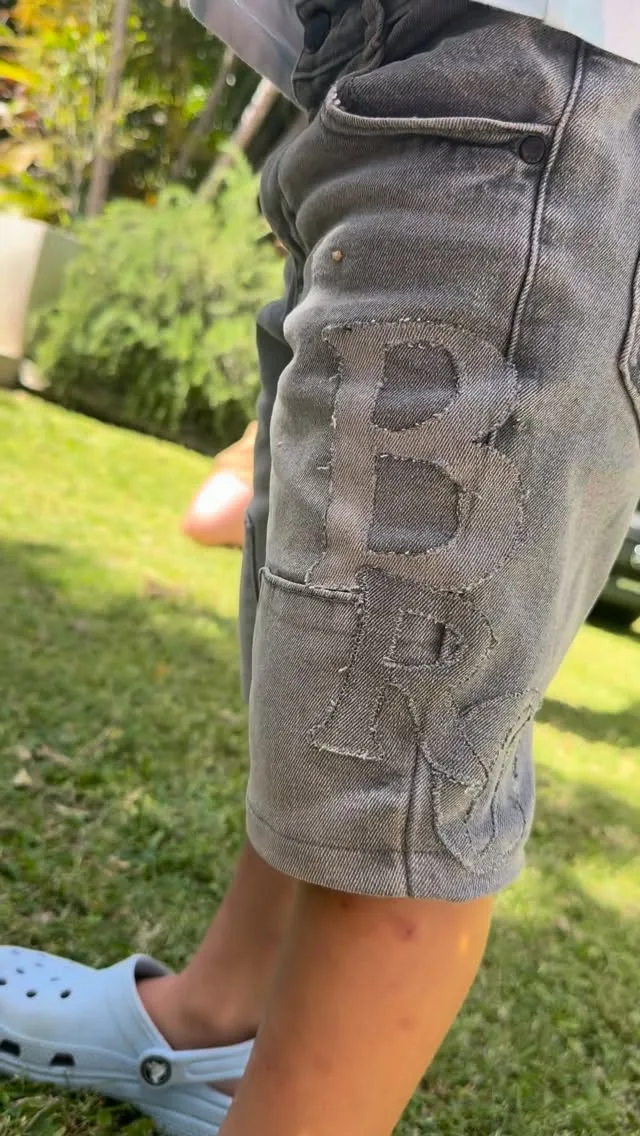 Grey denim shorts decorated with contrasting denim letter appliqué.